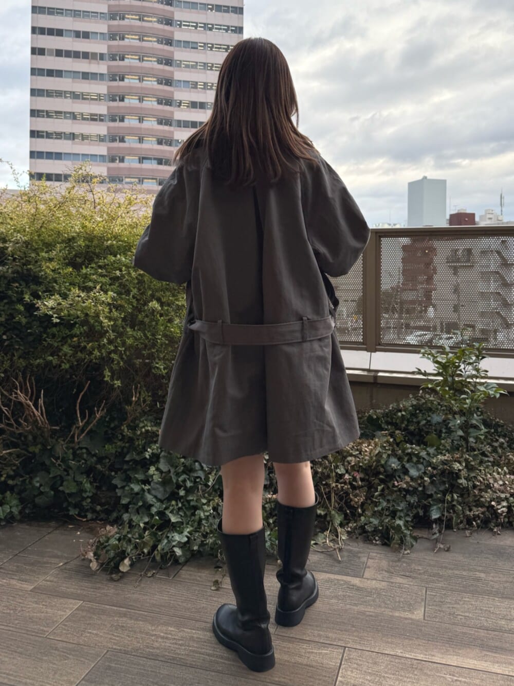 ホワイト系のシャツ/ブラウス、ブラック系のブーツ、グレー系のトレンチコートを着用したレディースの春コーディネートの3枚目の写真