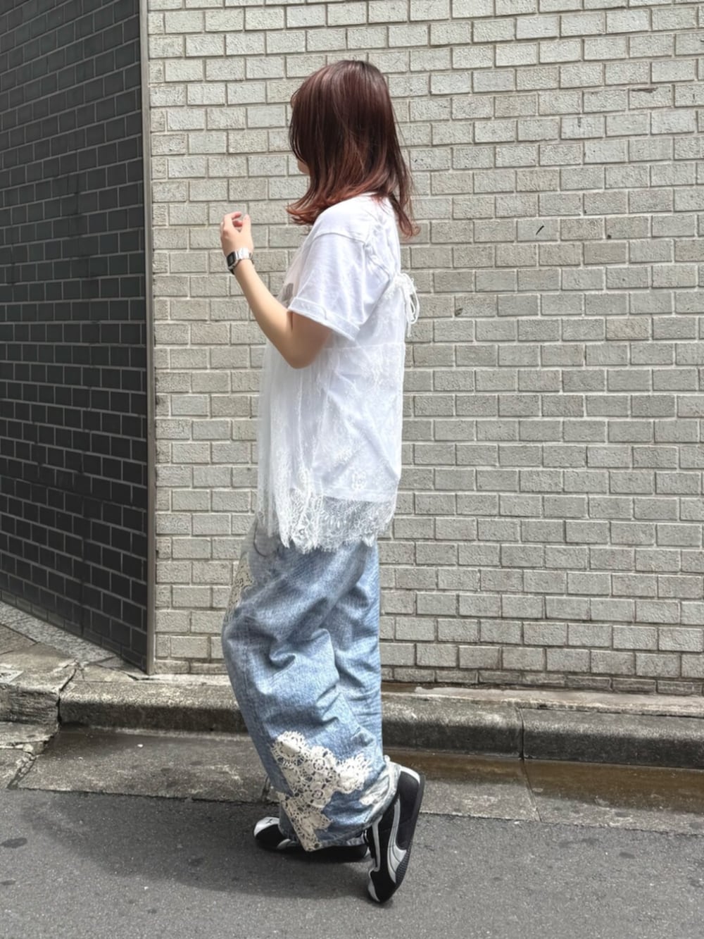 シルバー系のハンドバッグ、ブルー系のデニムパンツ、ホワイト系のキャミソールを着用したレディースの夏コーディネートの2枚目の写真