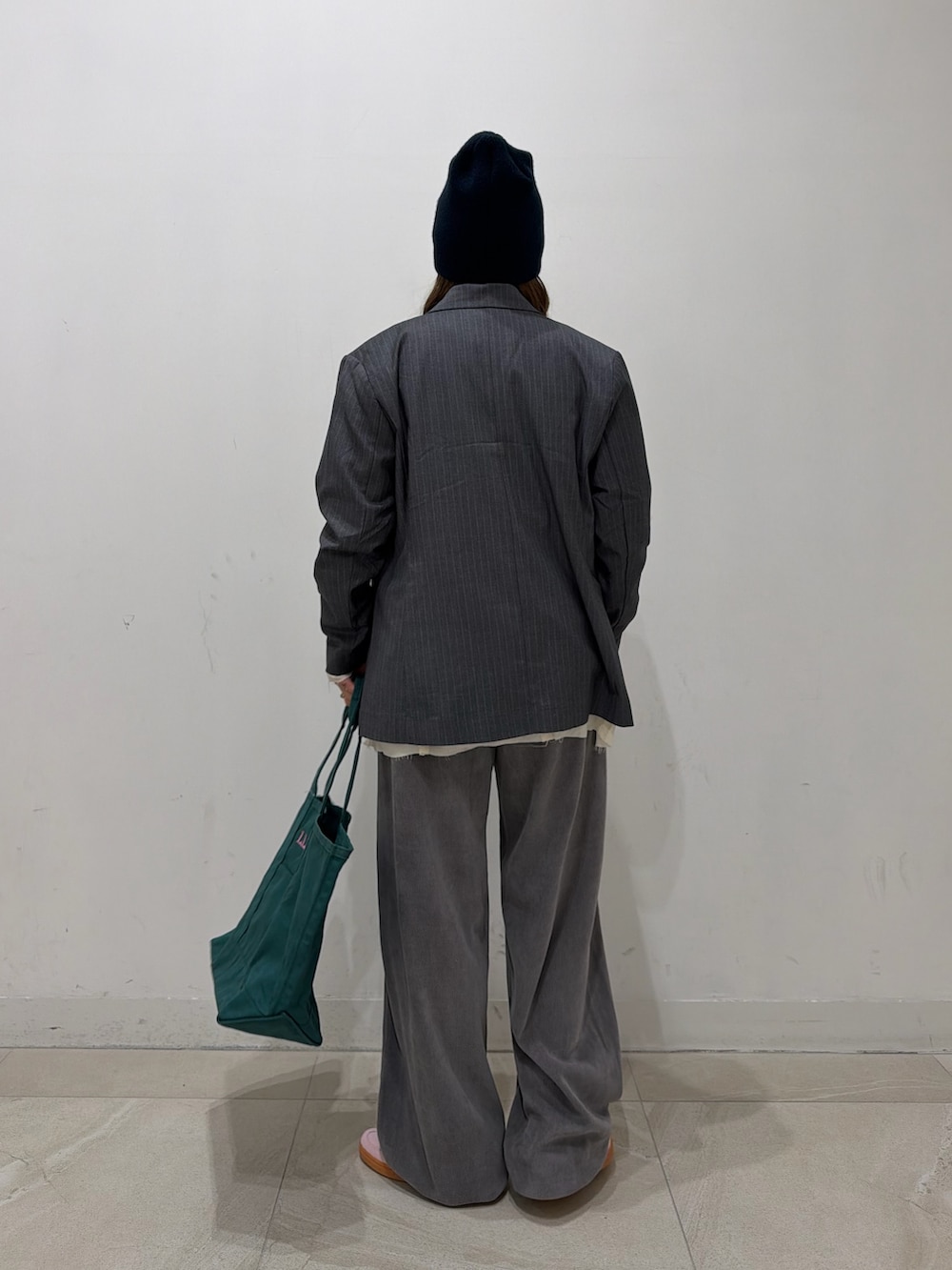 グレー系のテーラードジャケット、ホワイト系のTシャツ/カットソー、グリーン系のトートバッグを着用したレディースの冬コーディネートの2枚目の写真