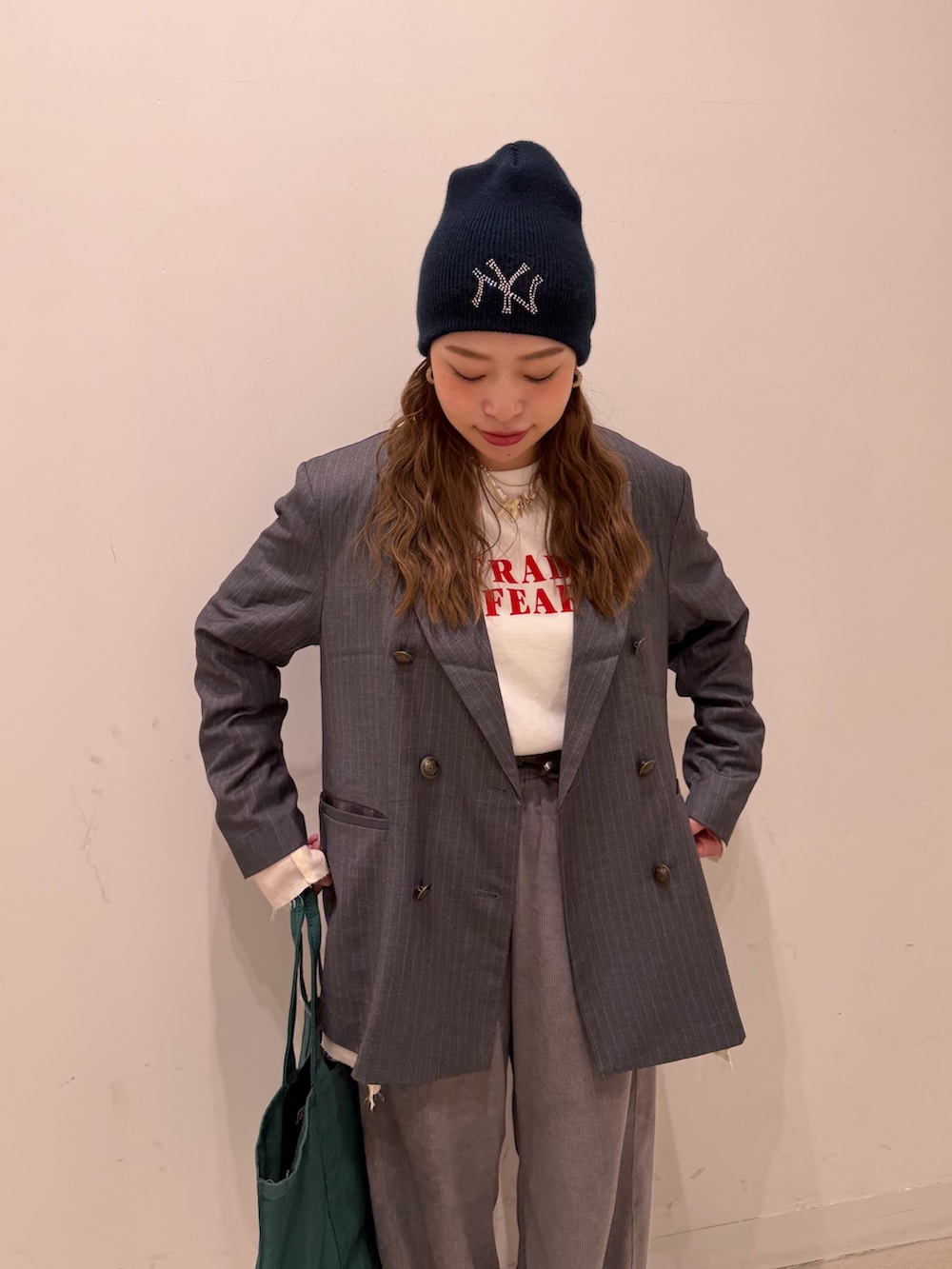 グレー系のテーラードジャケット、ホワイト系のTシャツ/カットソー、グリーン系のトートバッグを着用したレディースの冬コーディネートの3枚目の写真