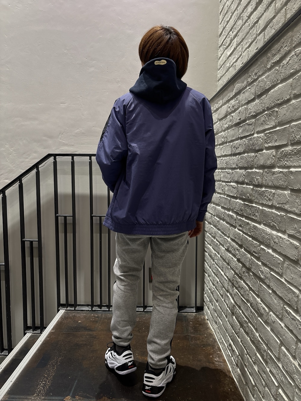 ホワイト系のスニーカー、ブラック系のトップス、ホワイト系のTシャツ/カットソーを着用したメンズの冬コーディネートの2枚目の写真