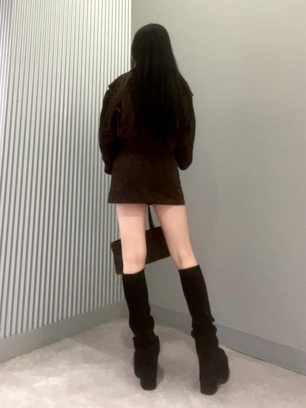 ブラック系のハンドバッグ、ブラック系のブーツ、ブラウン系のスカートを着用したレディースの秋コーディネートの3枚目の写真