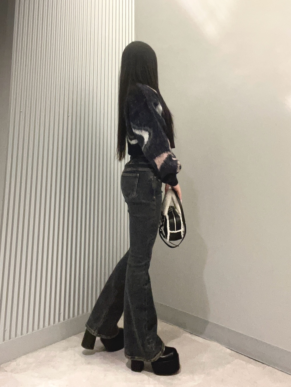 ブルー系のデニムパンツ、ブルー系のニット/セーター、ブラック系のハンドバッグを着用したレディースの秋コーディネートの2枚目の写真