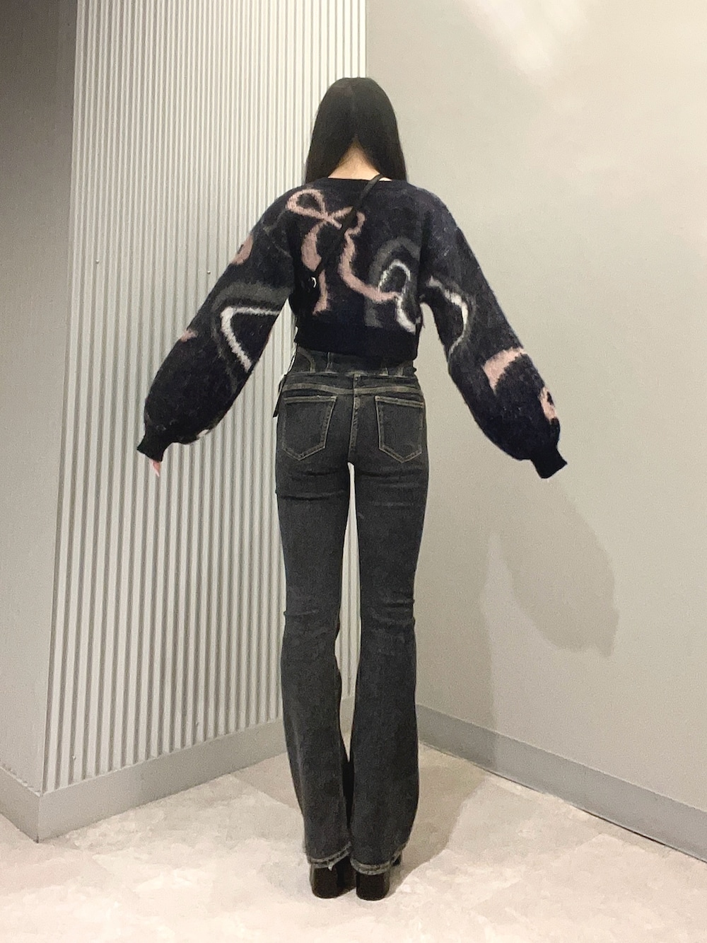 ブルー系のデニムパンツ、ブルー系のニット/セーター、ブラック系のハンドバッグを着用したレディースの秋コーディネートの3枚目の写真