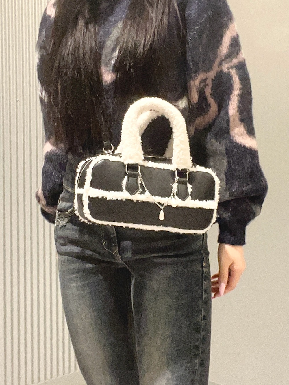 ブルー系のデニムパンツ、ブルー系のニット/セーター、ブラック系のハンドバッグを着用したレディースの秋コーディネートの4枚目の写真