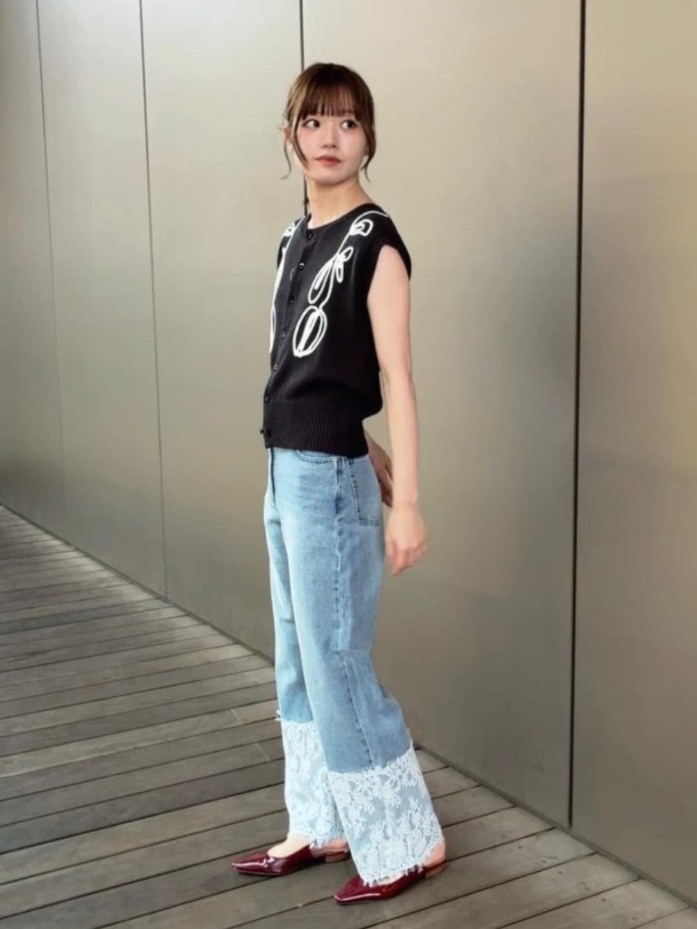 グレー系のベスト、ブルー系のデニムパンツを着用したレディースの夏コーディネートの2枚目の写真