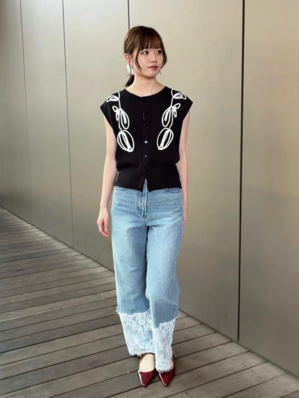 グレー系のベスト、ブルー系のデニムパンツを着用したレディースの夏コーディネートの3枚目の写真