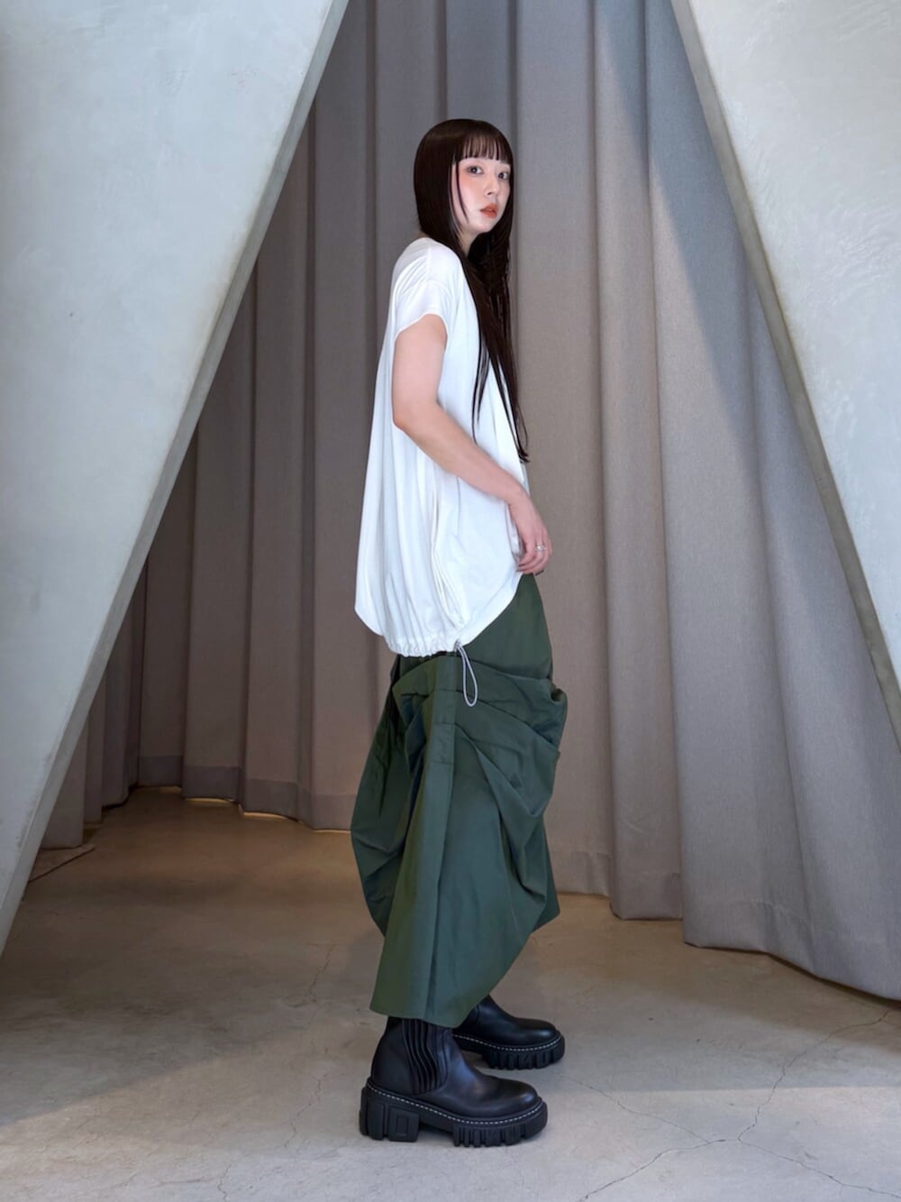 ホワイト系のTシャツ/カットソー、グリーン系のスカート、ブラック系のブーツを着用したレディースの秋コーディネートの4枚目の写真