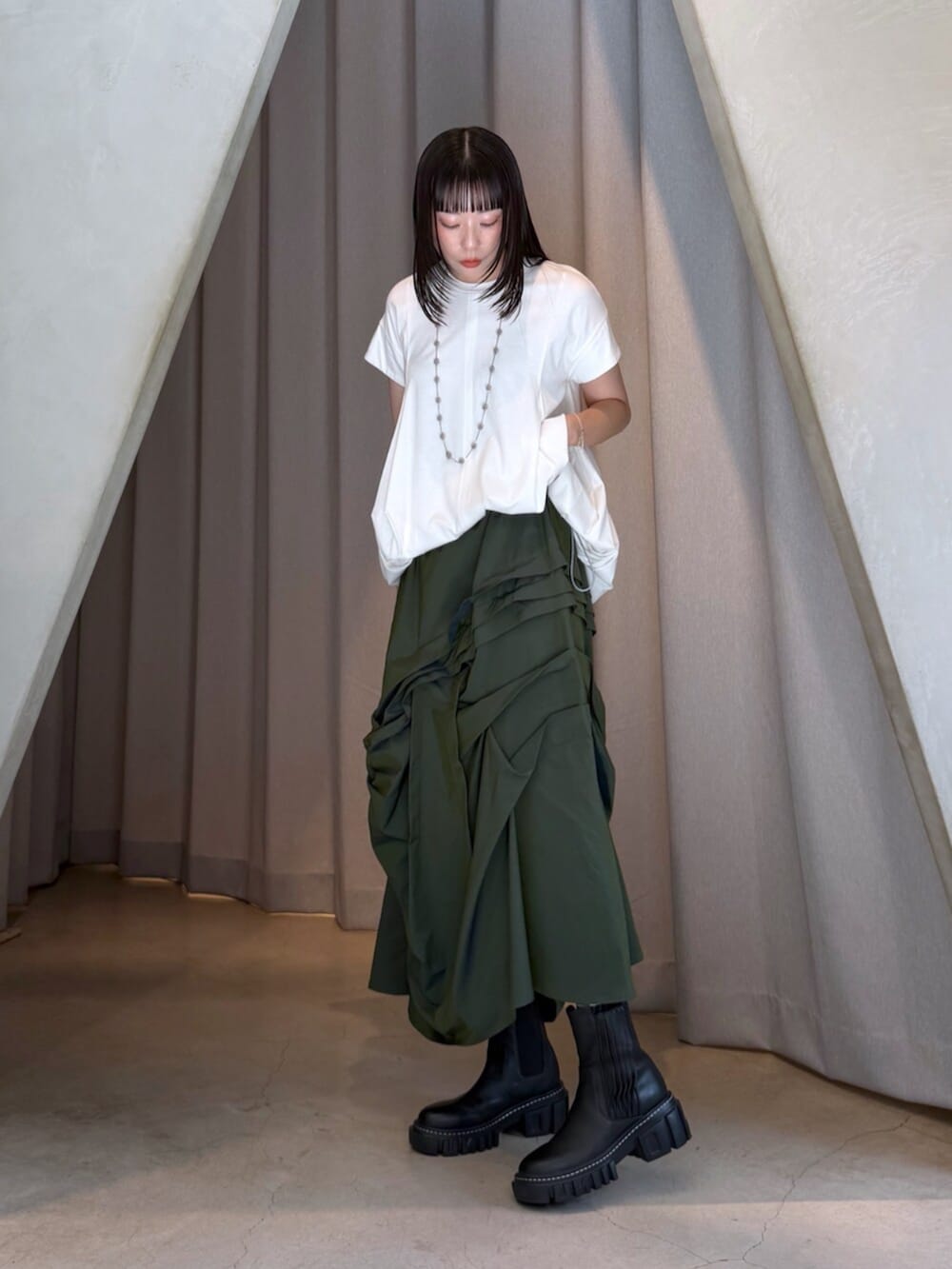 ホワイト系のTシャツ/カットソー、グリーン系のスカート、ブラック系のブーツを着用したレディースの秋コーディネートの5枚目の写真