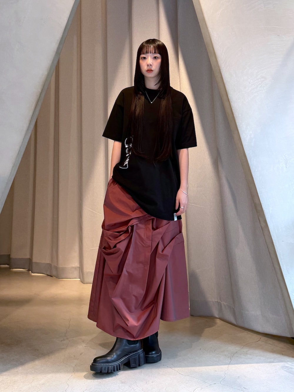 ブラック系のTシャツ/カットソー、レッド系のスカート、ブラック系のブーツを着用したレディースの秋コーディネートの7枚目の写真