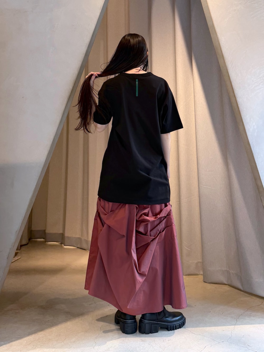 ブラック系のTシャツ/カットソー、レッド系のスカート、ブラック系のブーツを着用したレディースの秋コーディネートの3枚目の写真
