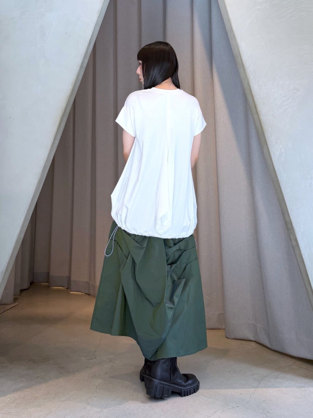 ホワイト系のTシャツ/カットソー、グリーン系のスカート、ブラック系のブーツを着用したレディースの秋コーディネートの3枚目の写真