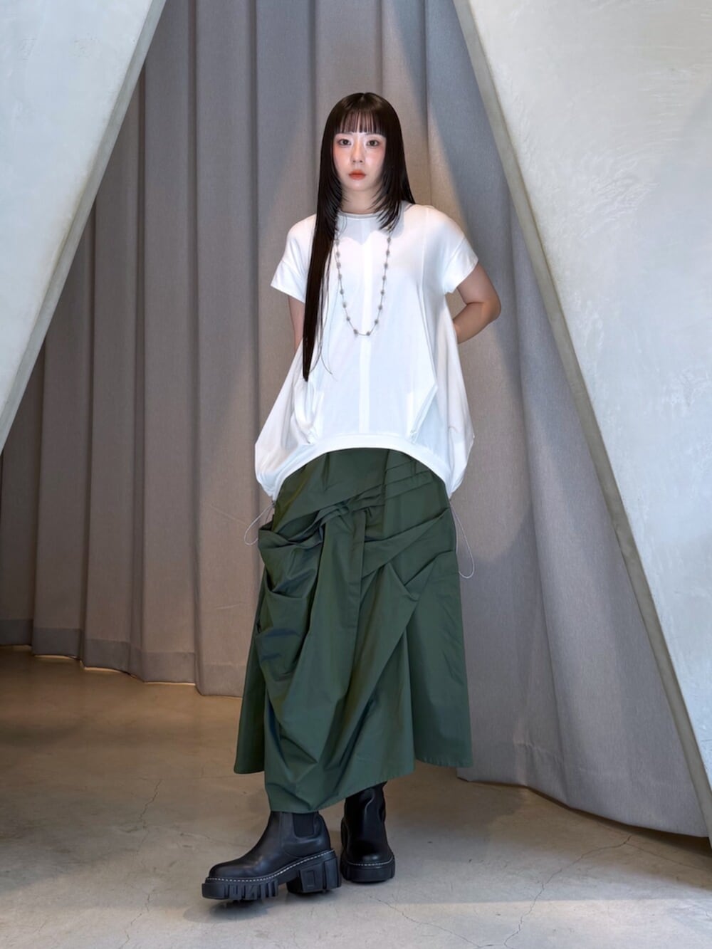 ホワイト系のTシャツ/カットソー、グリーン系のスカート、ブラック系のブーツを着用したレディースの秋コーディネートの7枚目の写真