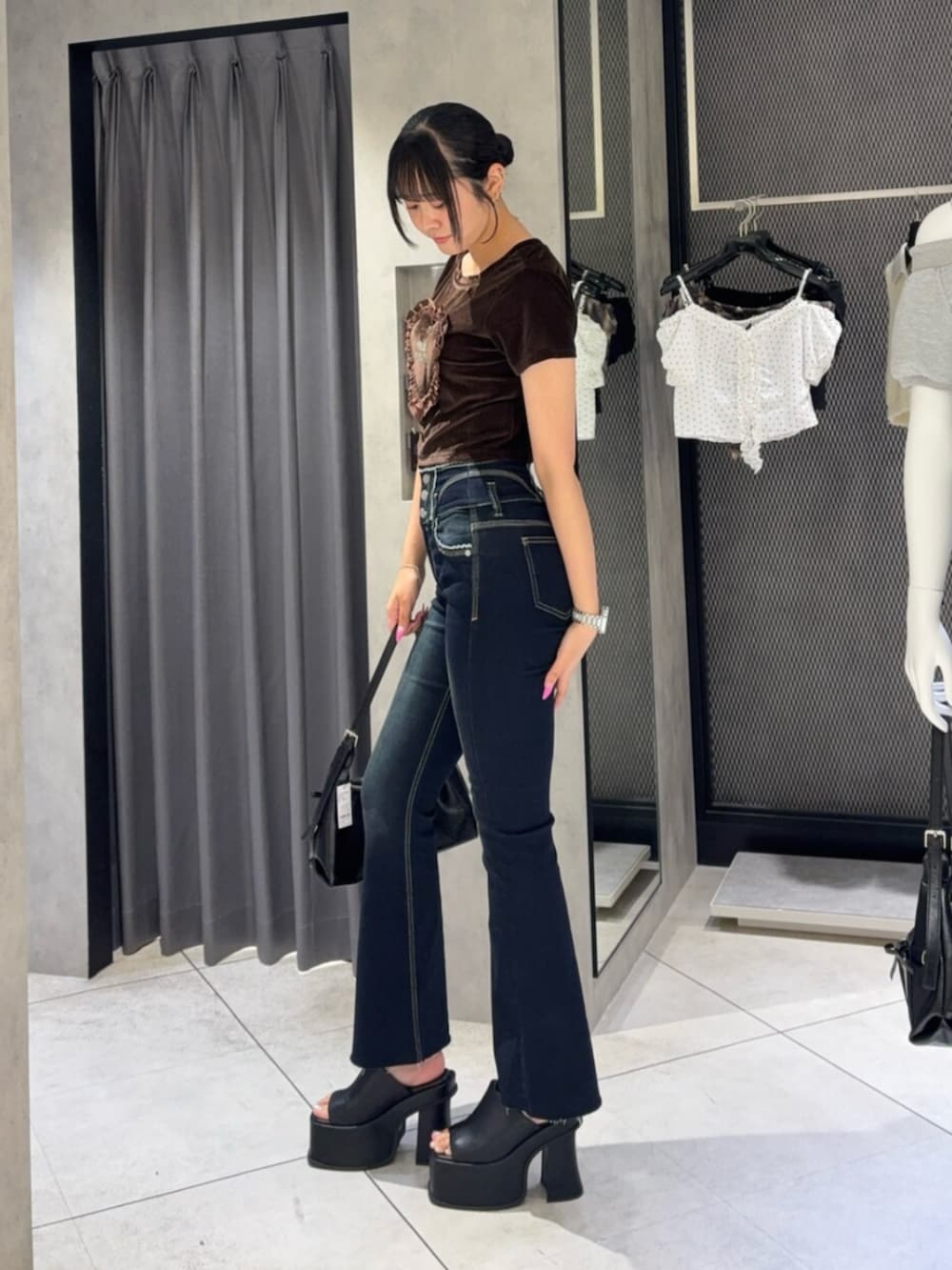 ブラック系のサンダル、ブラック系のハンドバッグ、ブルー系のデニムパンツを着用したレディースの夏コーディネートの2枚目の写真