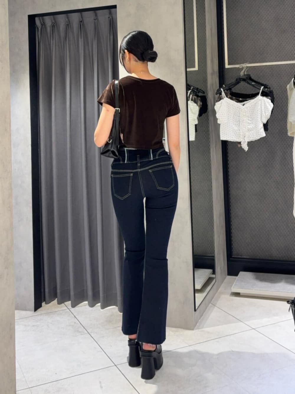 ブラック系のサンダル、ブラック系のハンドバッグ、ブルー系のデニムパンツを着用したレディースの夏コーディネートの3枚目の写真