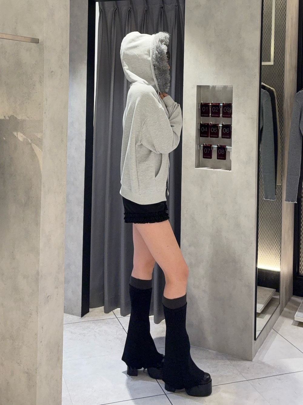 グレー系のパーカー、ブラック系のその他パンツ、ブラック系のレッグウォーマーを着用したレディースの秋コーディネートの2枚目の写真