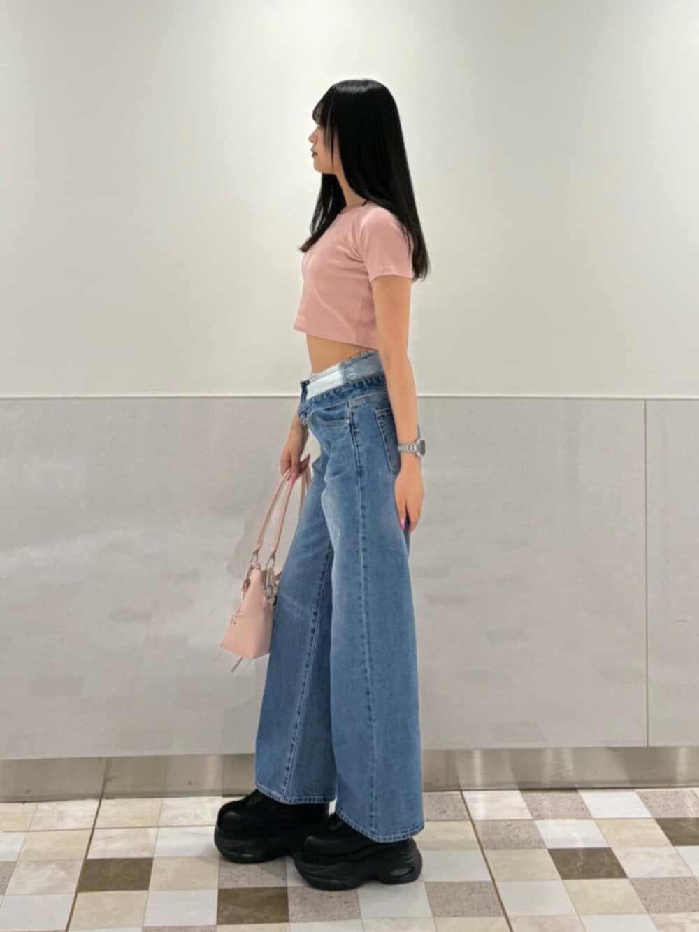 ピンク系のショルダーバッグ、ブルー系のデニムパンツ、ブラック系のスニーカーを着用したレディースの夏コーディネートの2枚目の写真