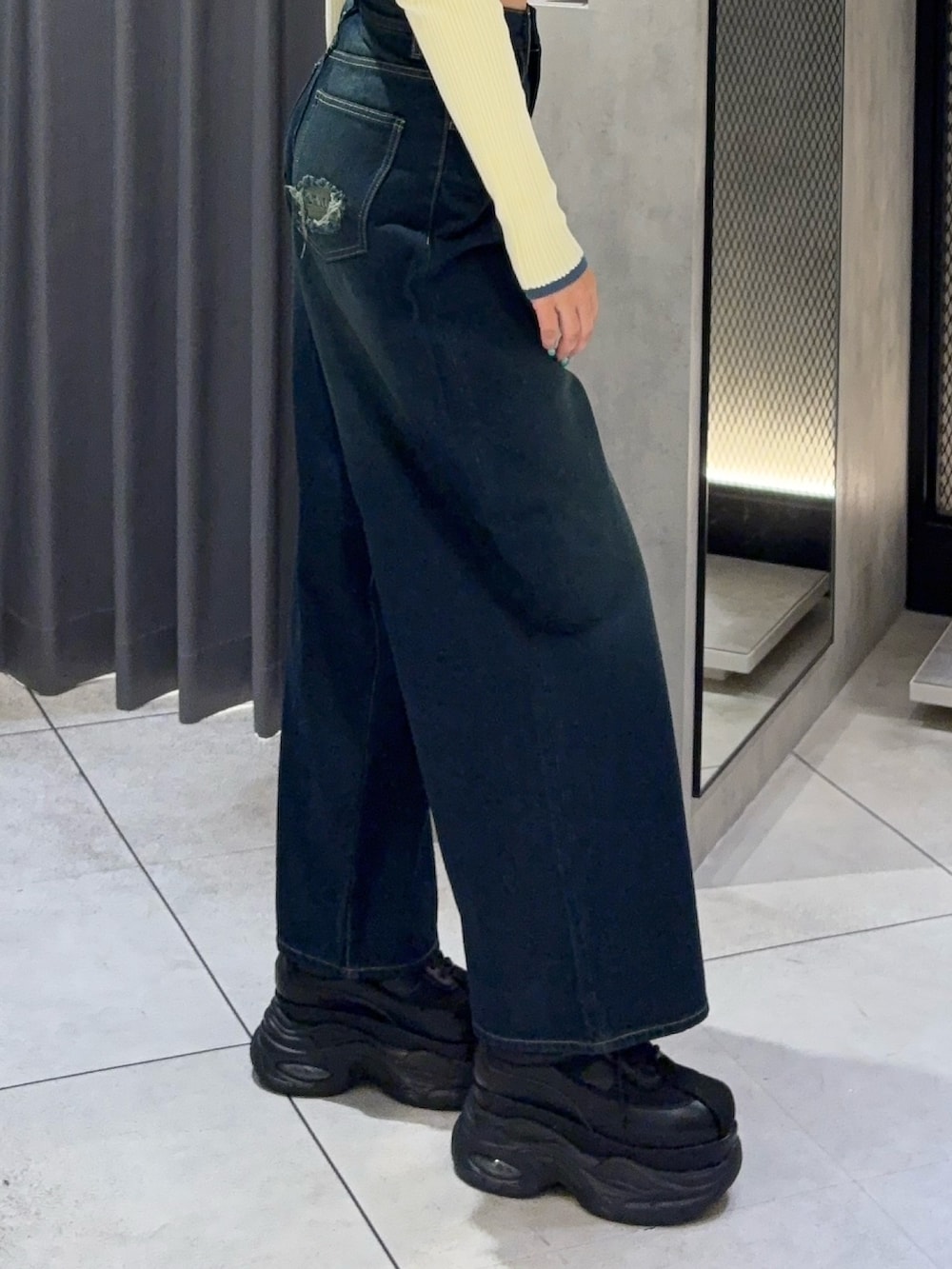 ホワイト系のニット/セーター、ブルー系のデニムパンツ、ブラック系のスニーカーを着用したレディースの秋コーディネートの5枚目の写真