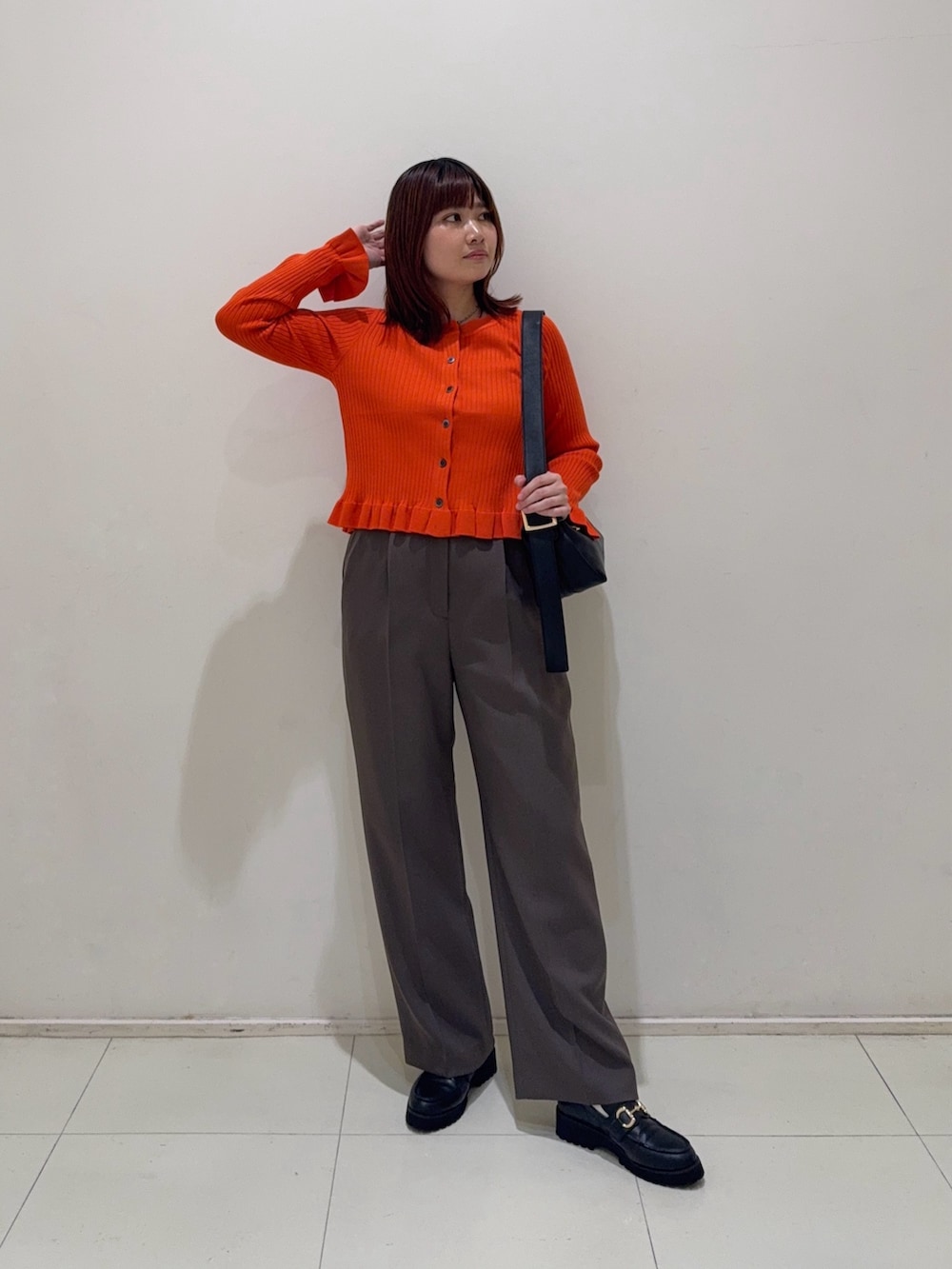 ブラウン系のその他パンツ、ブラック系のローファー、オレンジ系のニット/セーターを着用したレディースの秋コーディネートの2枚目の写真