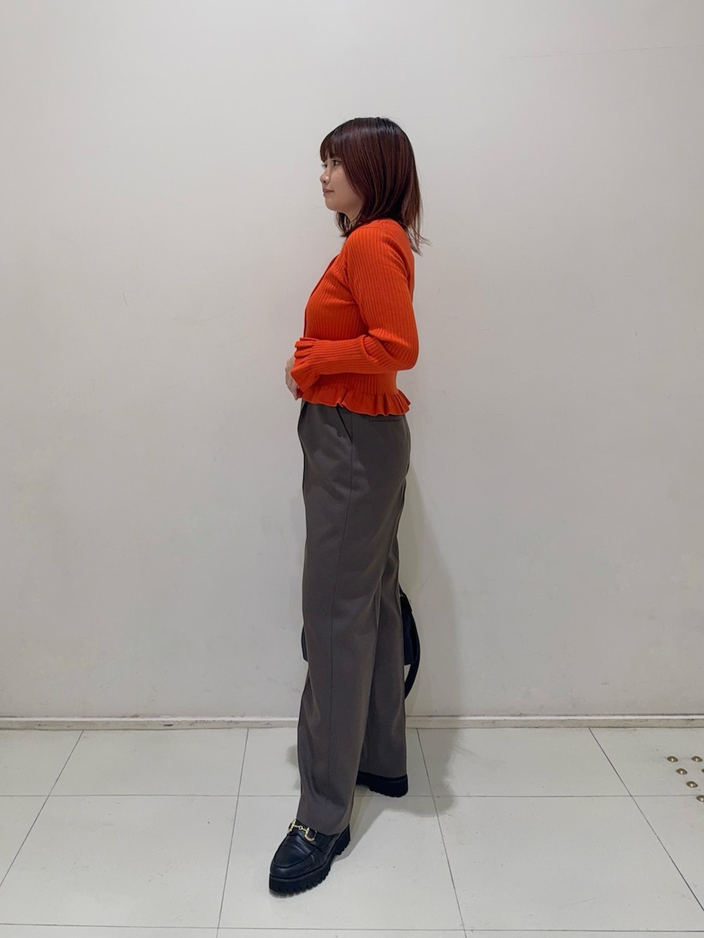 ブラウン系のその他パンツ、ブラック系のローファー、オレンジ系のニット/セーターを着用したレディースの秋コーディネートの3枚目の写真