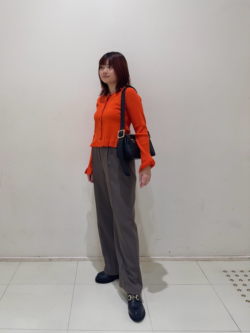 ブラウン系のその他パンツ、ブラック系のローファー、オレンジ系のニット/セーターを着用したレディースの秋コーディネートの4枚目の写真