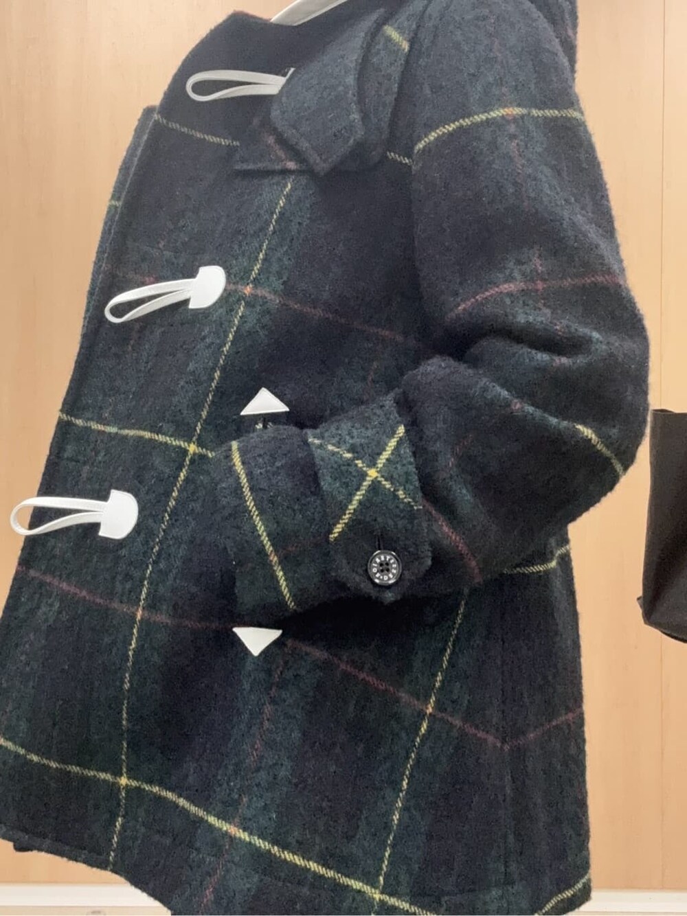 グリーン系のダッフルコート、ブルー系のデニムパンツ、ブラック系のカーディガン/ボレロを着用したレディースの秋コーディネートの5枚目の写真