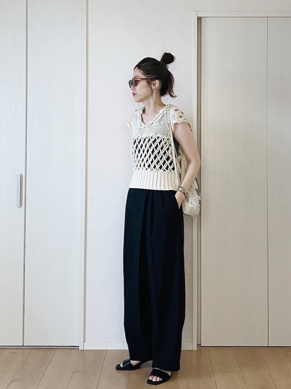 グレー系のタンクトップ、ブラック系のスラックス、ホワイト系のベストを着用したレディースの夏コーディネートの2枚目の写真