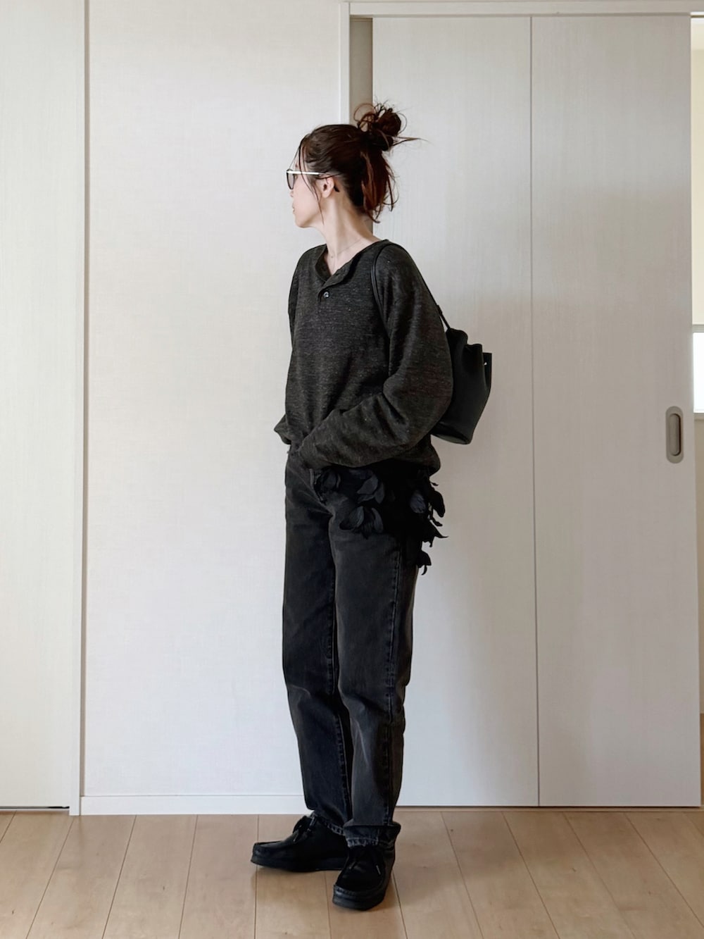 ブラック系のデニムパンツ、ブラック系のモカシン/デッキシューズ、グレー系のニット/セーターを着用したレディースの春コーディネートの3枚目の写真