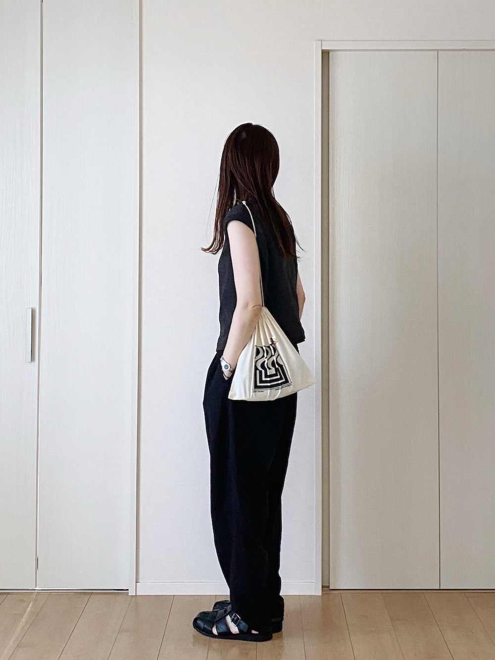 ブラック系のタンクトップ、ブラック系のサンダル、ブラック系のパンツを着用したレディースの秋コーディネートの3枚目の写真