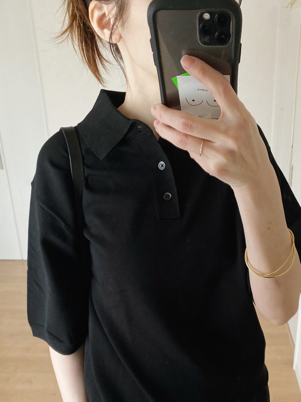 ブラック系のポロシャツ、ブラック系のハンドバッグ、ブラック系のパンツを着用したレディースの春コーディネートの3枚目の写真