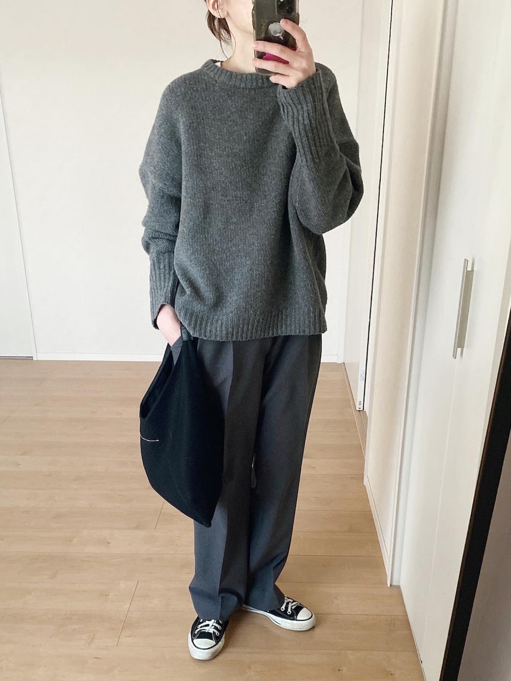 グレー系のニット/セーター、グレー系のスラックス、ブラック系のハンドバッグを着用したレディースの春コーディネートの2枚目の写真