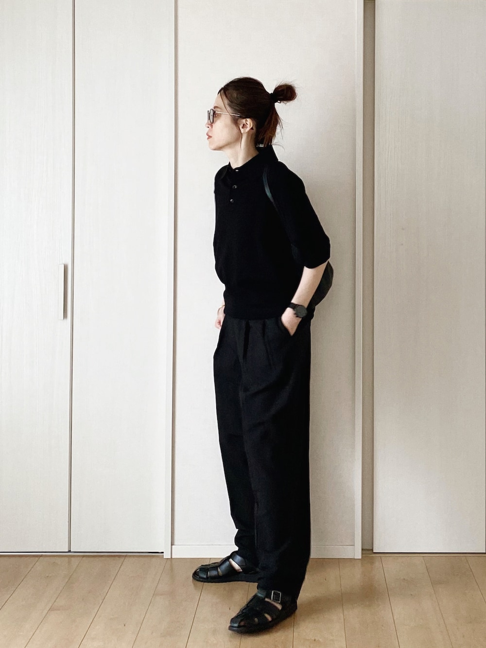 ブラック系のポロシャツ、ブラック系のハンドバッグ、ブラック系のパンツを着用したレディースの春コーディネートの2枚目の写真