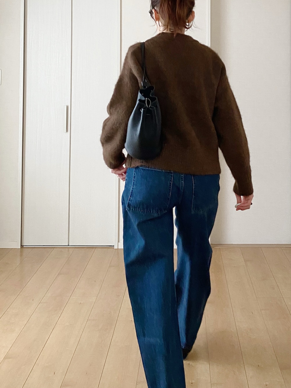 ブラック系のショルダーバッグ、ブラック系のモカシン/デッキシューズ、ブルー系のデニムパンツを着用したレディースの冬コーディネートの4枚目の写真