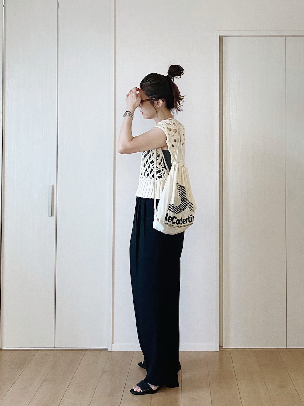 グレー系のタンクトップ、ブラック系のスラックス、ホワイト系のベストを着用したレディースの夏コーディネートの4枚目の写真