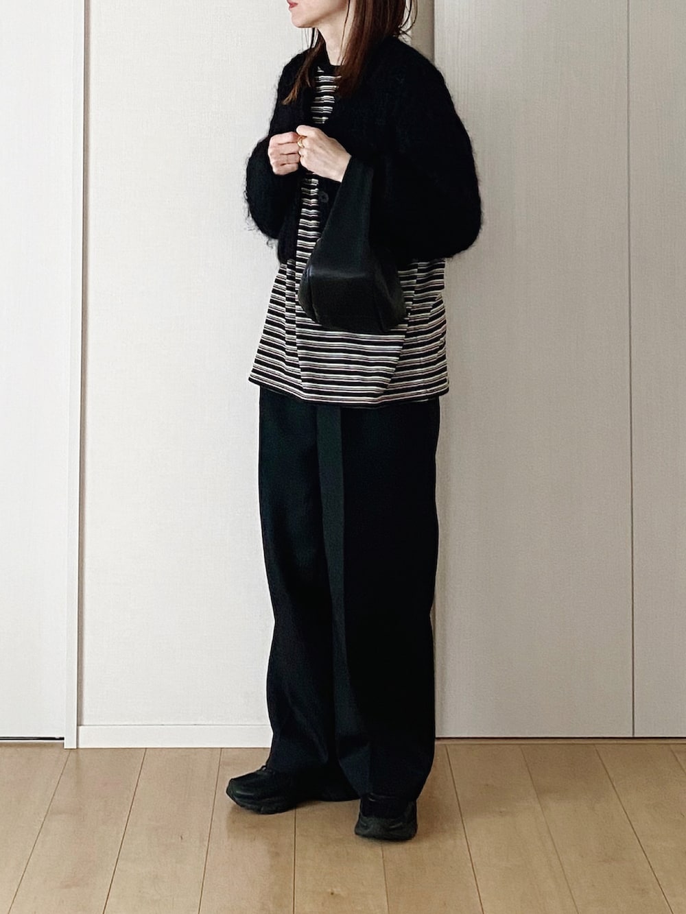 ブラック系のカーディガン/ボレロ、ブラック系のTシャツ/カットソー、ブラック系のハンドバッグを着用したレディースの冬コーディネートの3枚目の写真