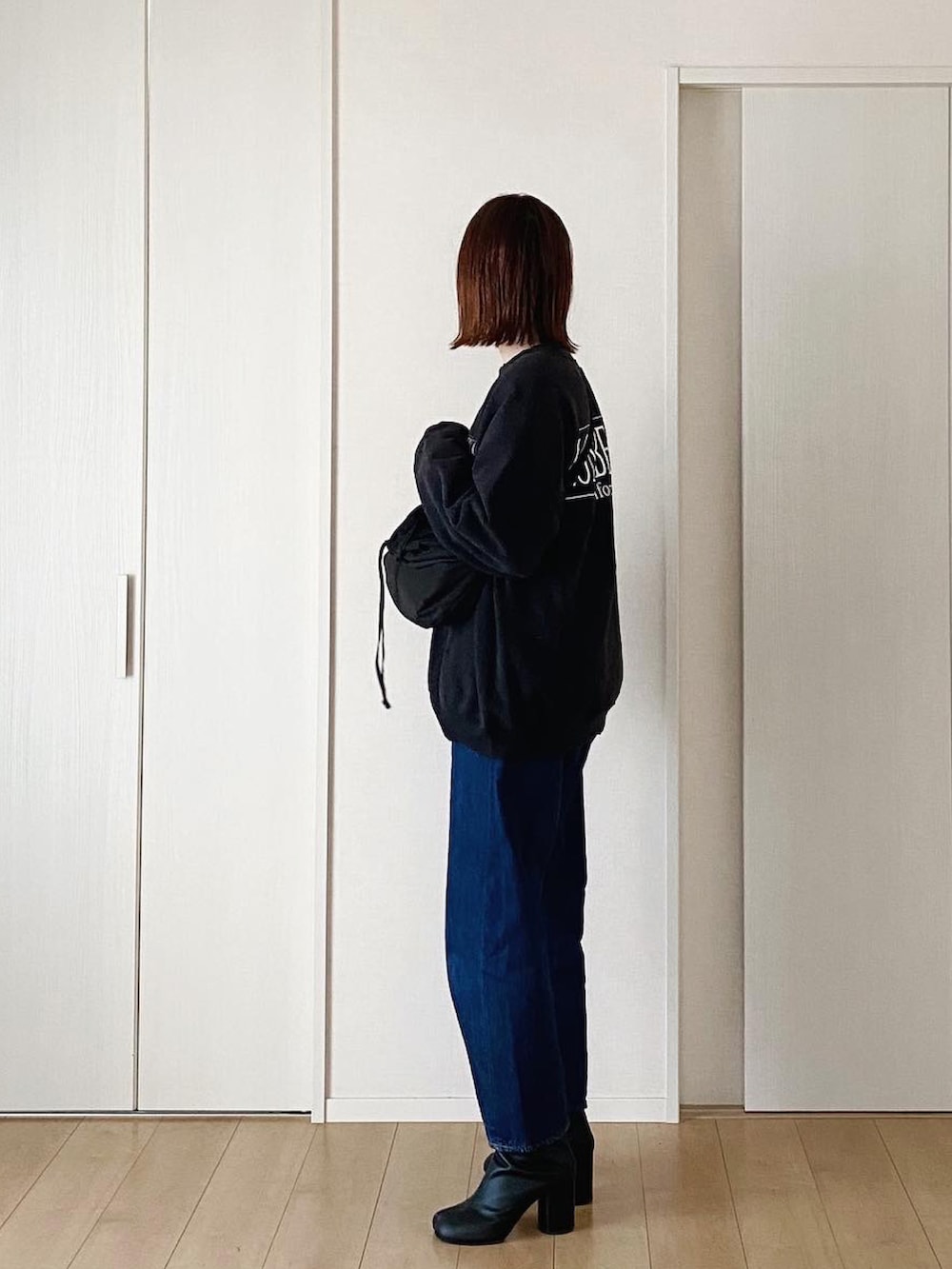 ブラック系のショルダーバッグ、ブラック系のスウェット、ホワイト系のTシャツ/カットソーを着用したレディースの冬コーディネートの2枚目の写真