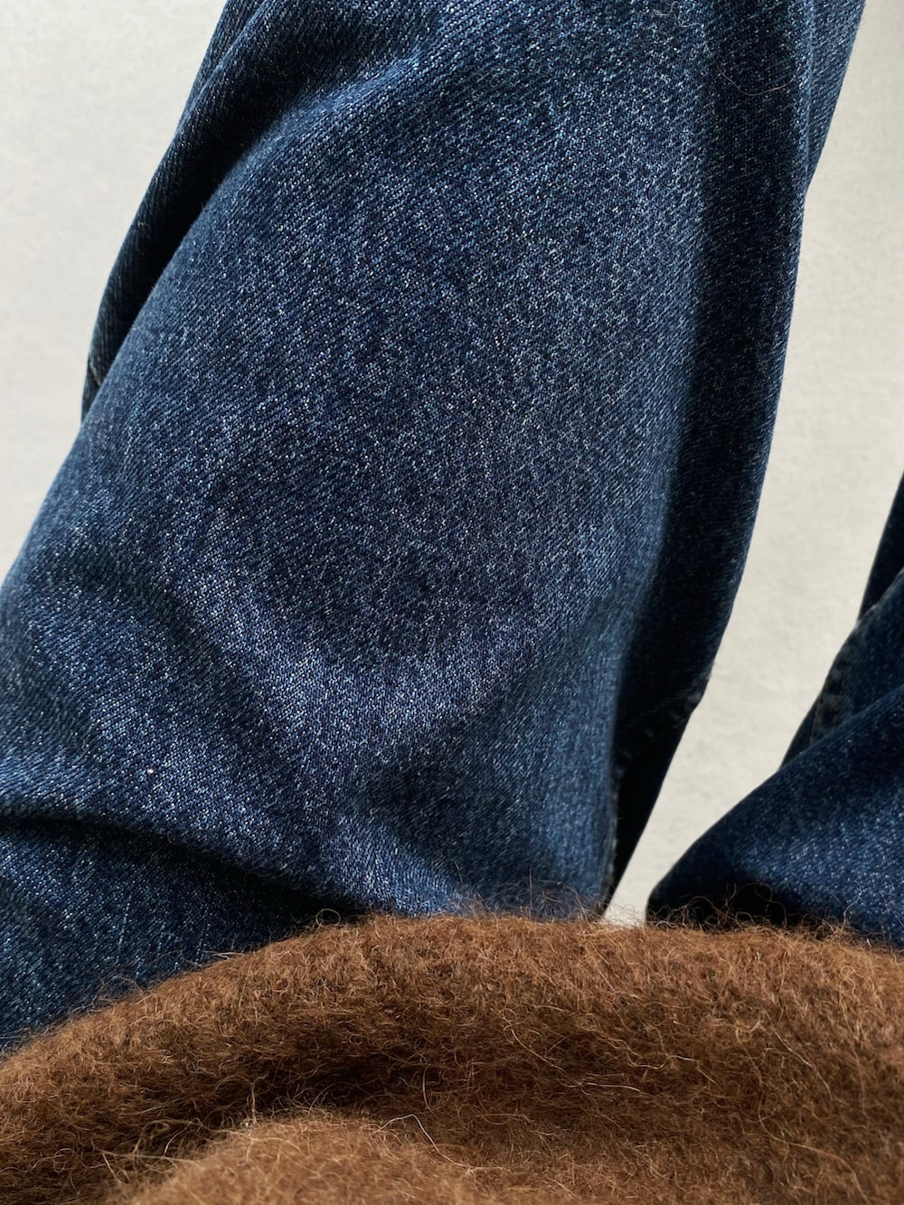 ブラック系のショルダーバッグ、ブラック系のモカシン/デッキシューズ、ブルー系のデニムパンツを着用したレディースの冬コーディネートの5枚目の写真