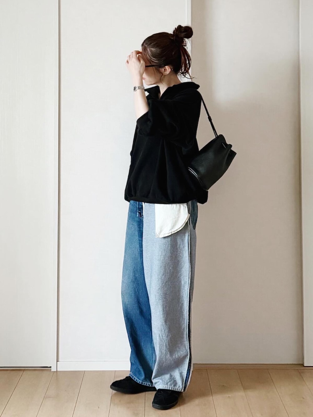 ブラック系のスウェット、ブルー系のデニムパンツ、ブラック系のショルダーバッグを着用したレディースの春コーディネートの2枚目の写真
