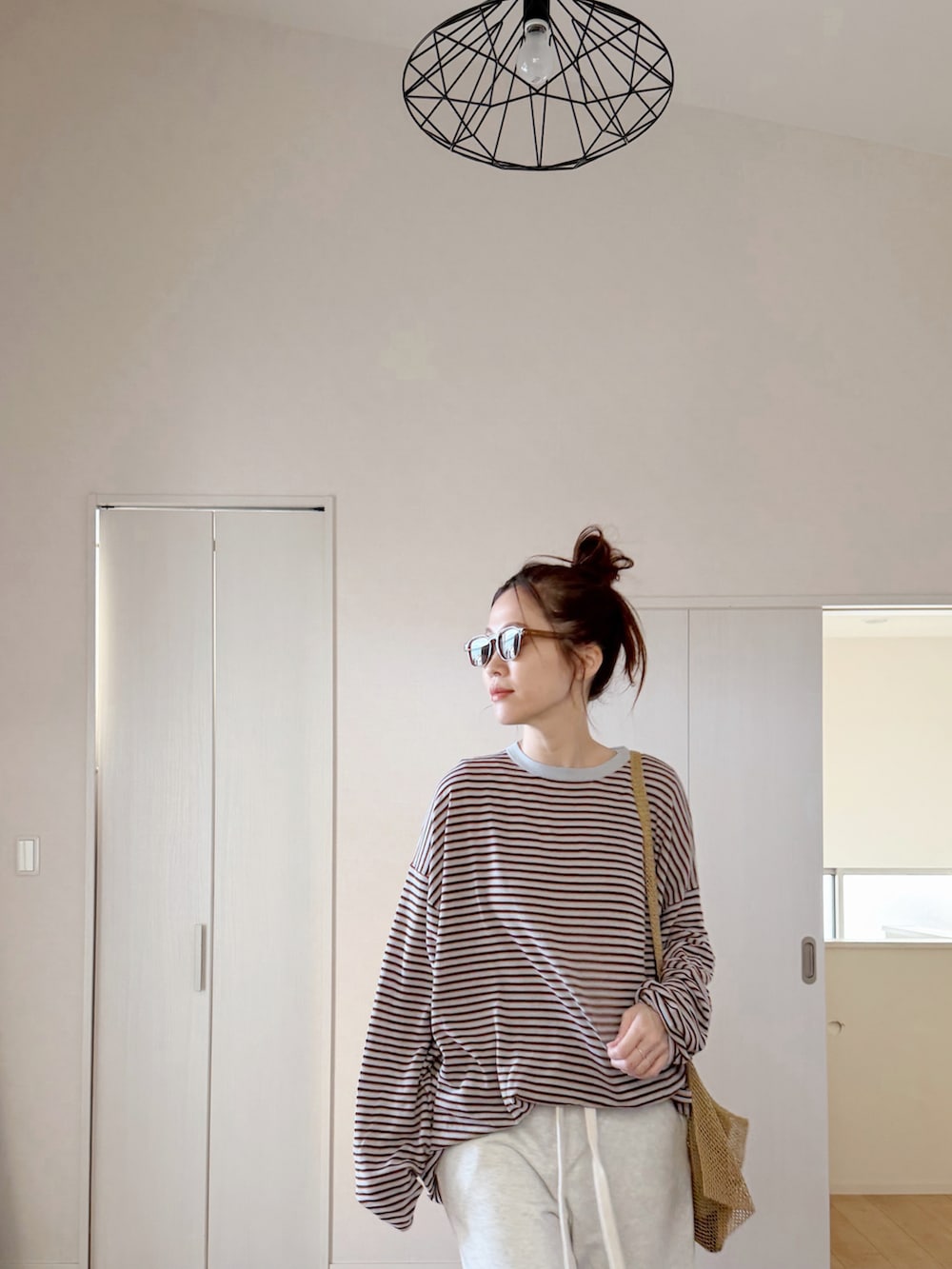 グレー系のニット/セーター、ホワイト系のスウェットパンツ、ベージュ系のショルダーバッグを着用したレディースの春コーディネートの5枚目の写真