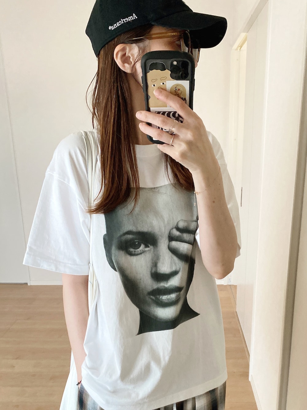 ホワイト系のTシャツ/カットソー、ホワイト系のエコバッグ/サブバッグ、ブラック系のスニーカーを着用したレディースの秋コーディネートの2枚目の写真