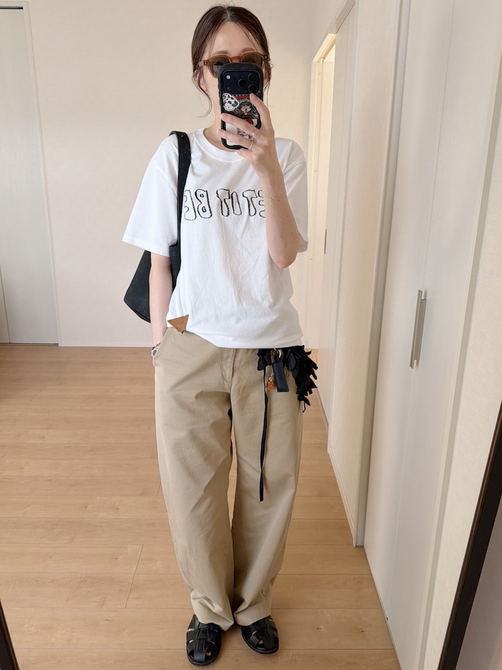 ホワイト系のTシャツ/カットソー、ブラック系のトートバッグ、その他のチノパンツを着用したレディースの秋コーディネートの4枚目の写真