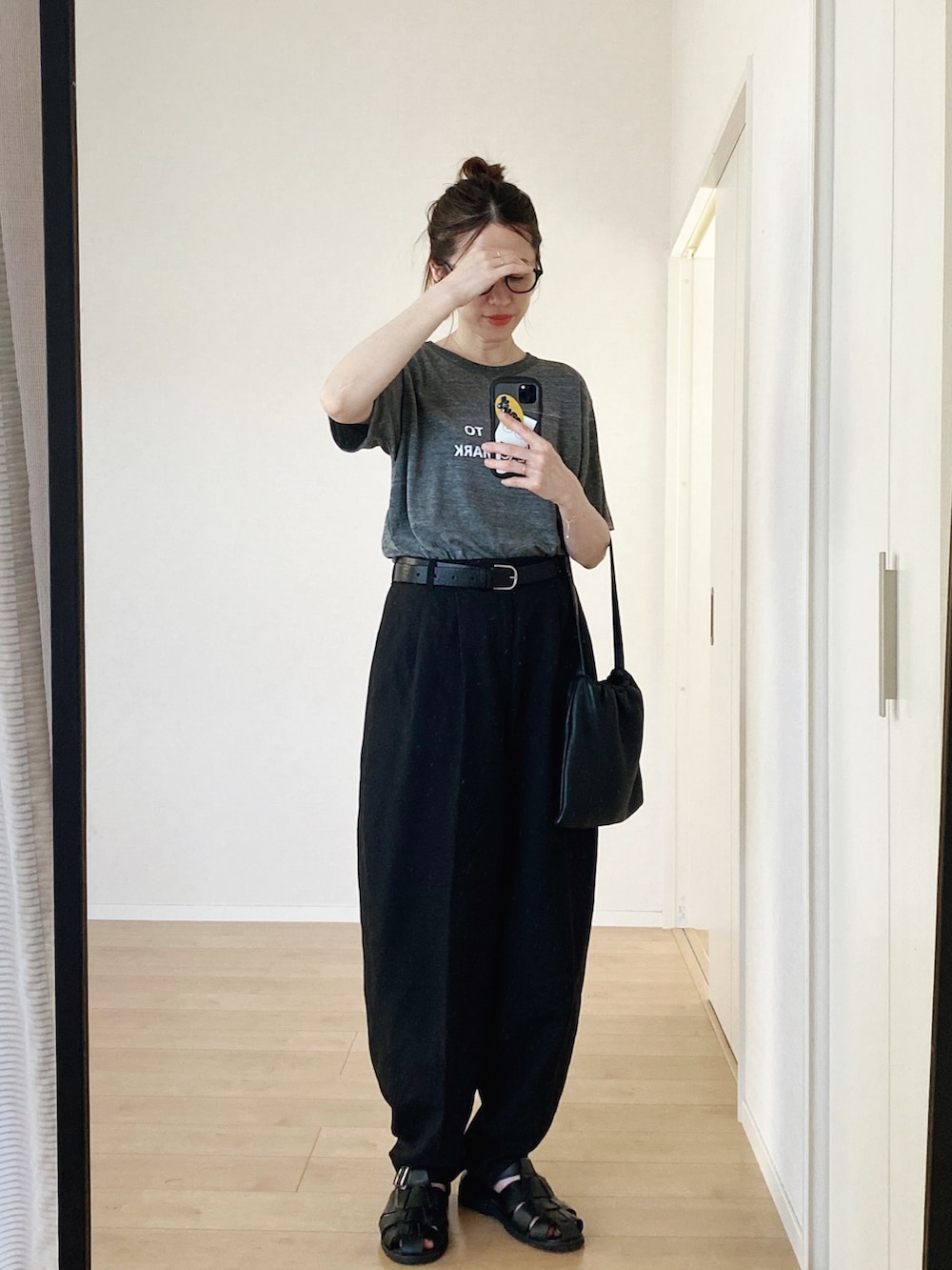 グレー系のTシャツ/カットソー、ブラック系のハンドバッグ、ブラック系のパンツを着用したレディースの夏コーディネートの3枚目の写真