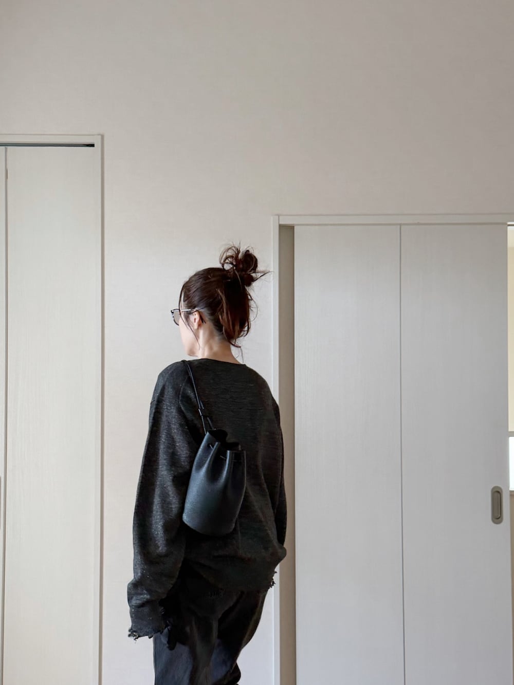 ブラック系のデニムパンツ、ブラック系のモカシン/デッキシューズ、グレー系のニット/セーターを着用したレディースの春コーディネートの5枚目の写真