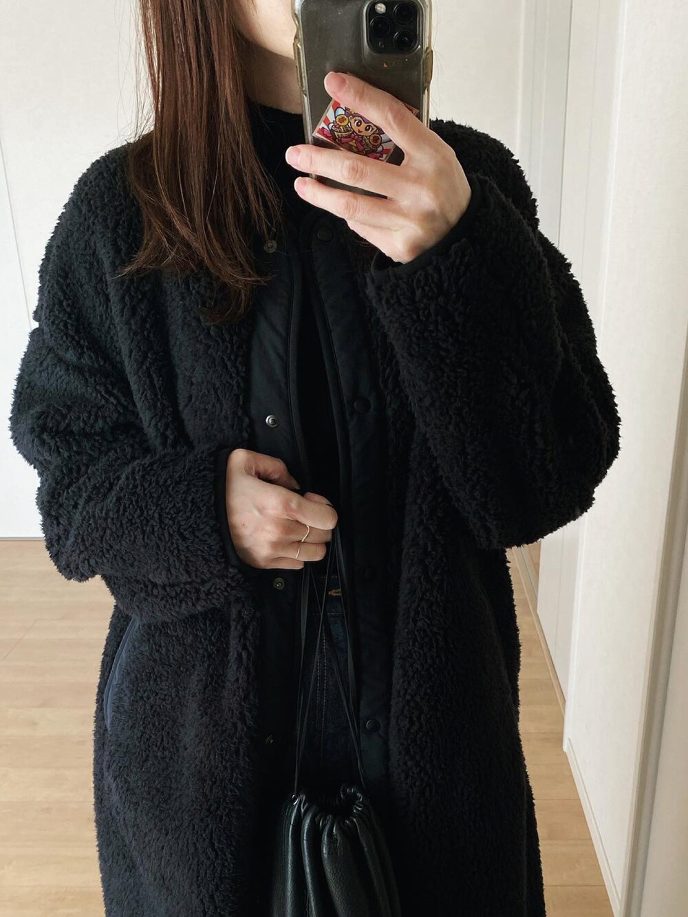 ブラック系のニット/セーター、ブルー系のデニムパンツ、ブラック系のハンドバッグを着用したレディースの冬コーディネートの3枚目の写真