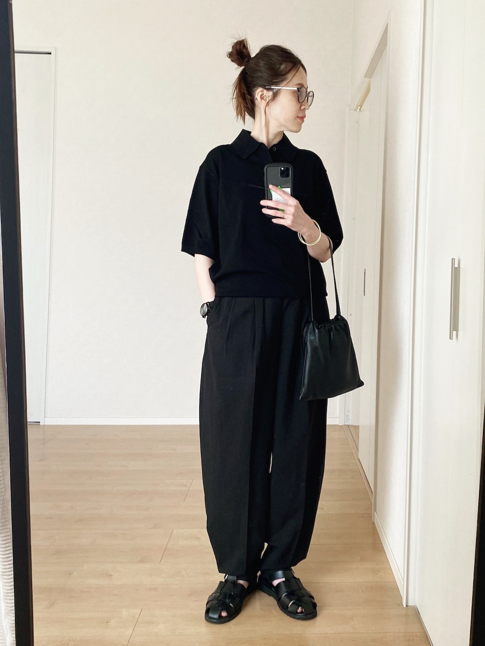 ブラック系のポロシャツ、ブラック系のハンドバッグ、ブラック系のパンツを着用したレディースの春コーディネートの4枚目の写真