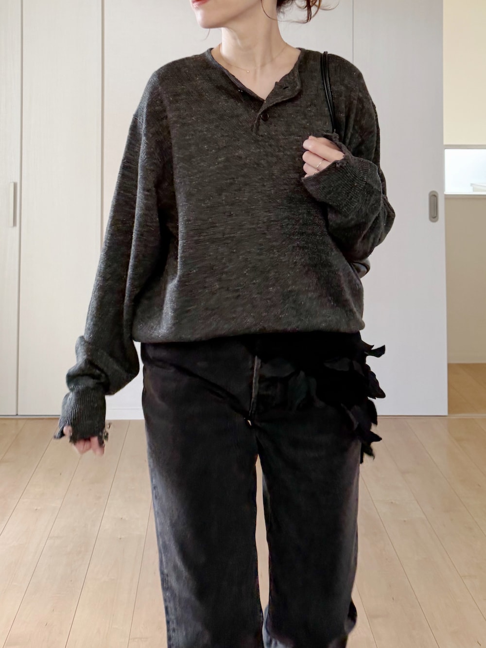 ブラック系のデニムパンツ、ブラック系のモカシン/デッキシューズ、グレー系のニット/セーターを着用したレディースの春コーディネートの2枚目の写真