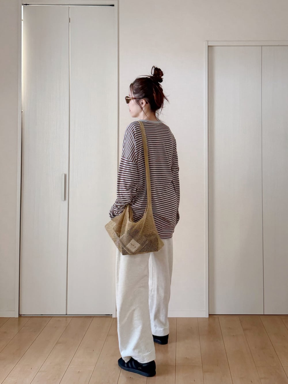 グレー系のニット/セーター、ホワイト系のスウェットパンツ、ベージュ系のショルダーバッグを着用したレディースの春コーディネートの4枚目の写真