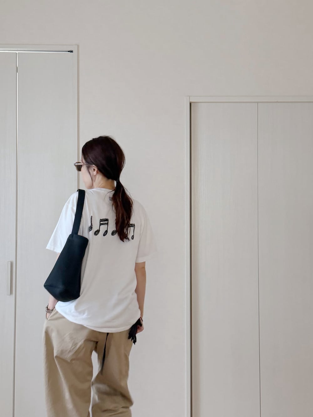 ホワイト系のTシャツ/カットソー、ブラック系のトートバッグ、その他のチノパンツを着用したレディースの秋コーディネートの2枚目の写真
