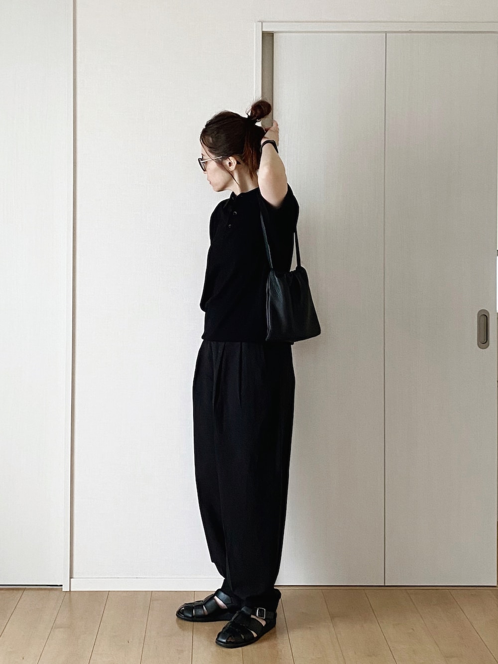 ブラック系のポロシャツ、ブラック系のハンドバッグ、ブラック系のパンツを着用したレディースの春コーディネートの5枚目の写真
