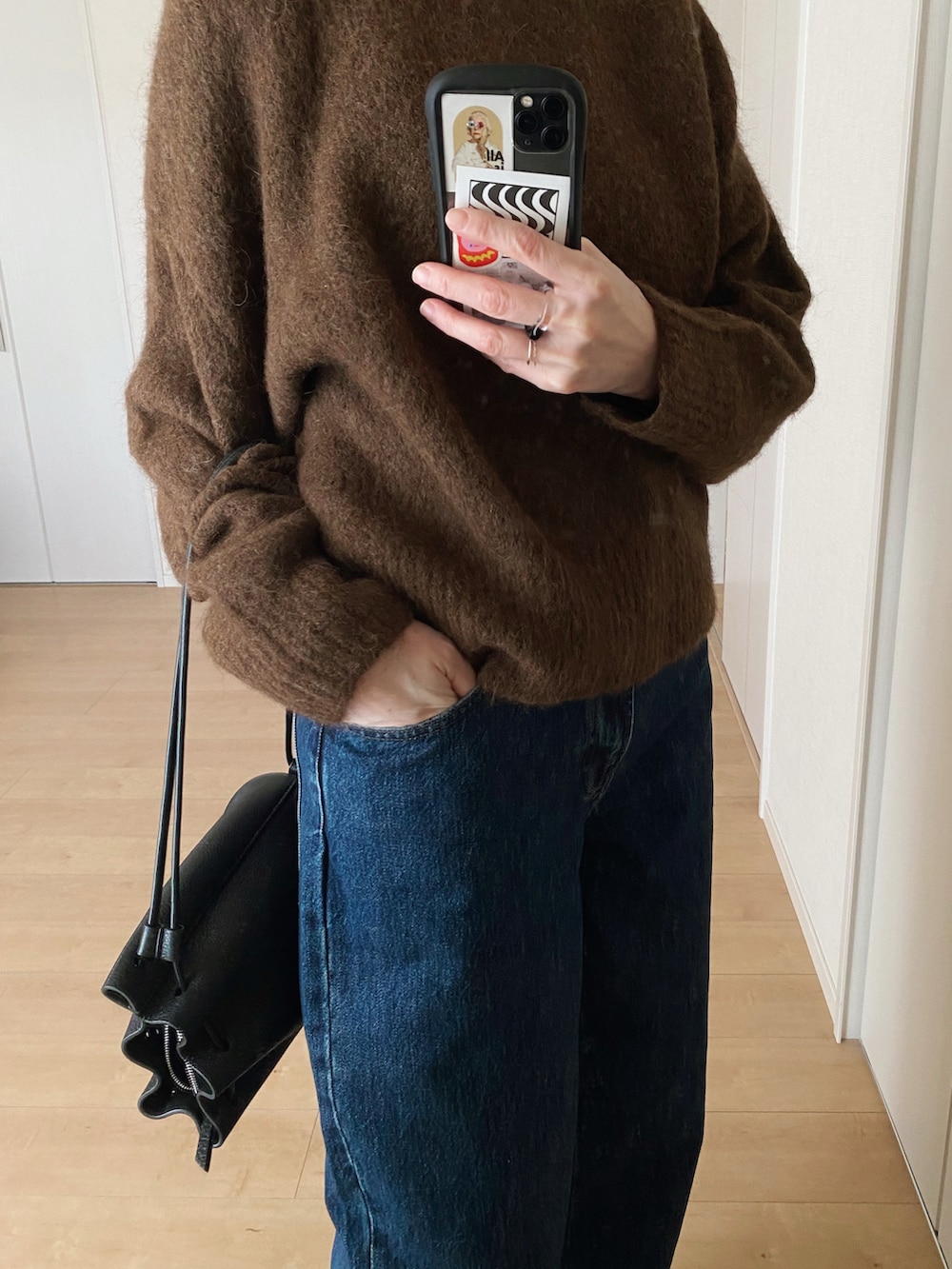 ブラック系のショルダーバッグ、ブラック系のモカシン/デッキシューズ、ブルー系のデニムパンツを着用したレディースの冬コーディネートの2枚目の写真